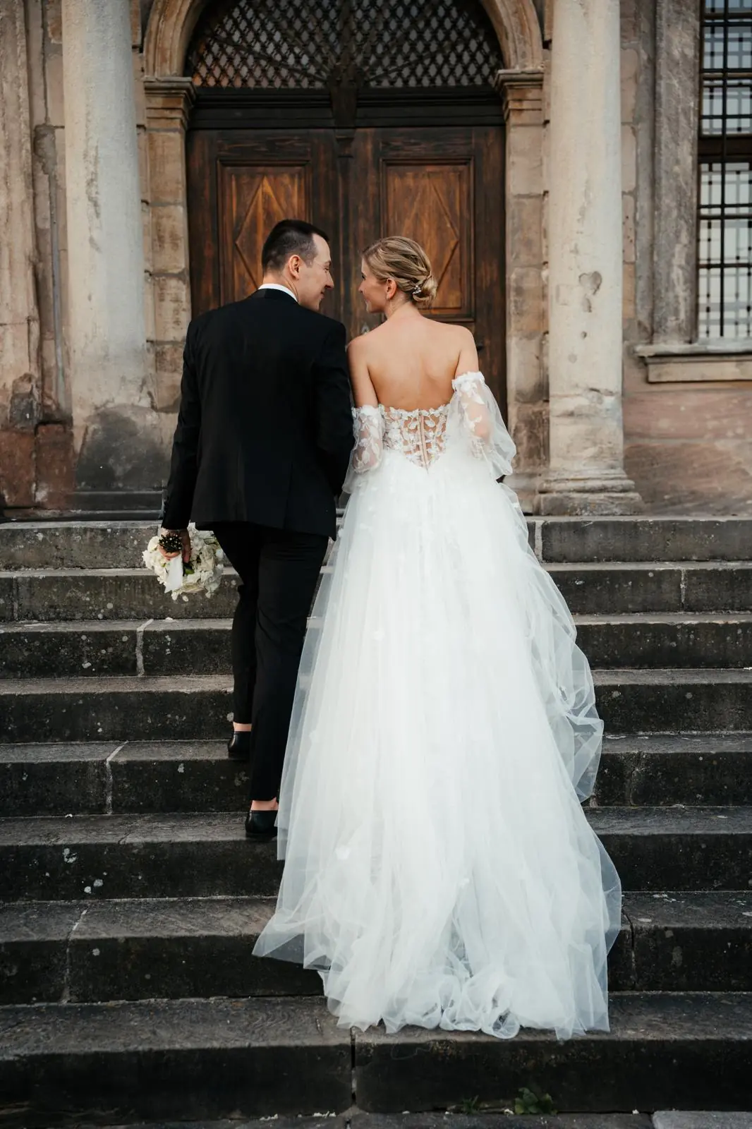 Brautpaar auf Treppe von Schloss Hemhofen mit Brautstrauß