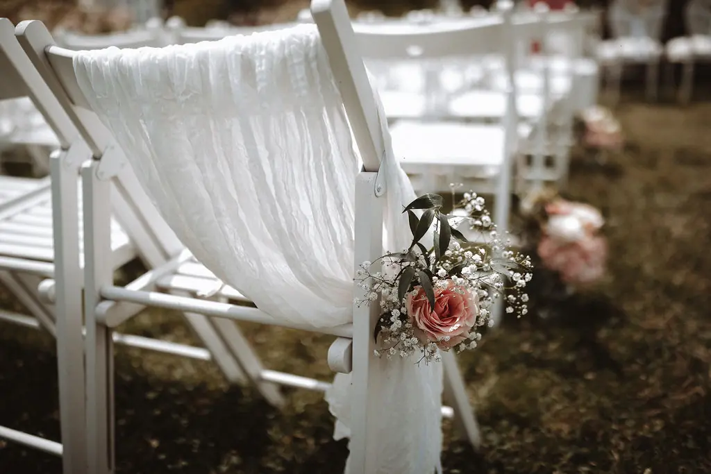 Stuhldekoration mit Schleierkraut und Rosen bei freier Trauung
