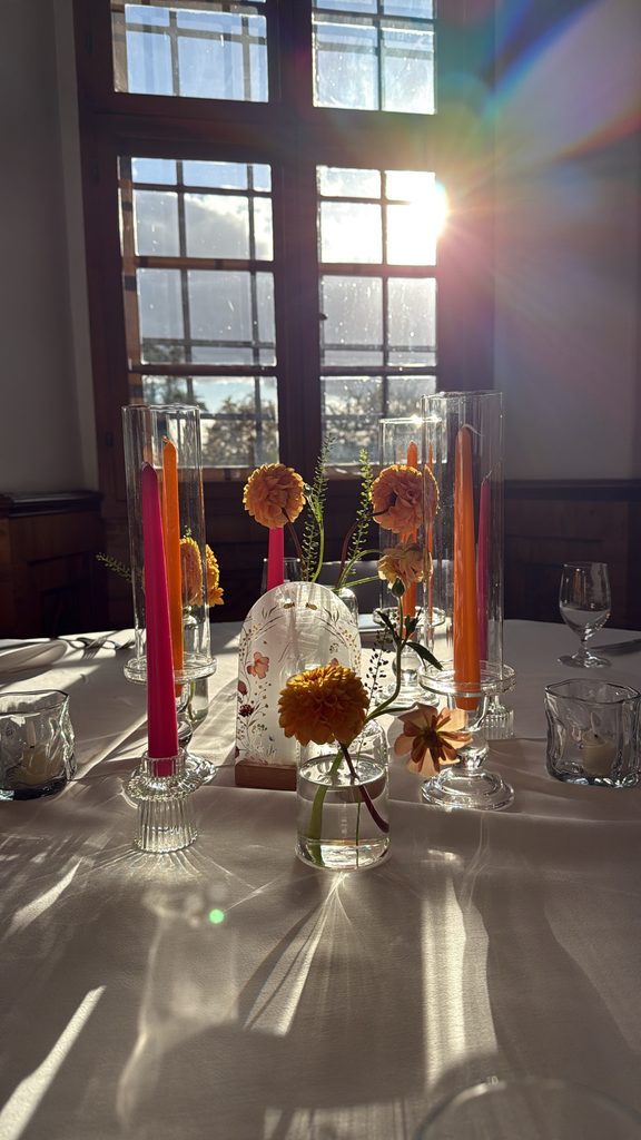 Farbenfrohe Hochzeitsdekoration mit orangefarbenen Blüten und pinkfarbenen Kerzen im Schloss Hemhofen